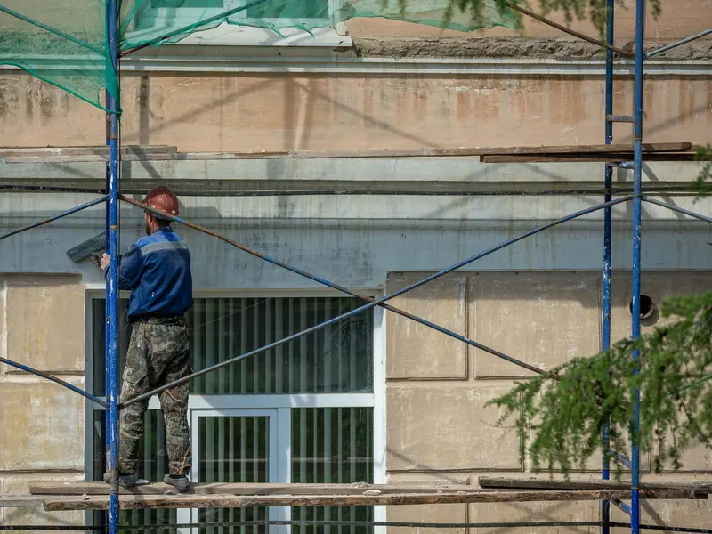 Radnik na skeli popravlja fasadu zgrade